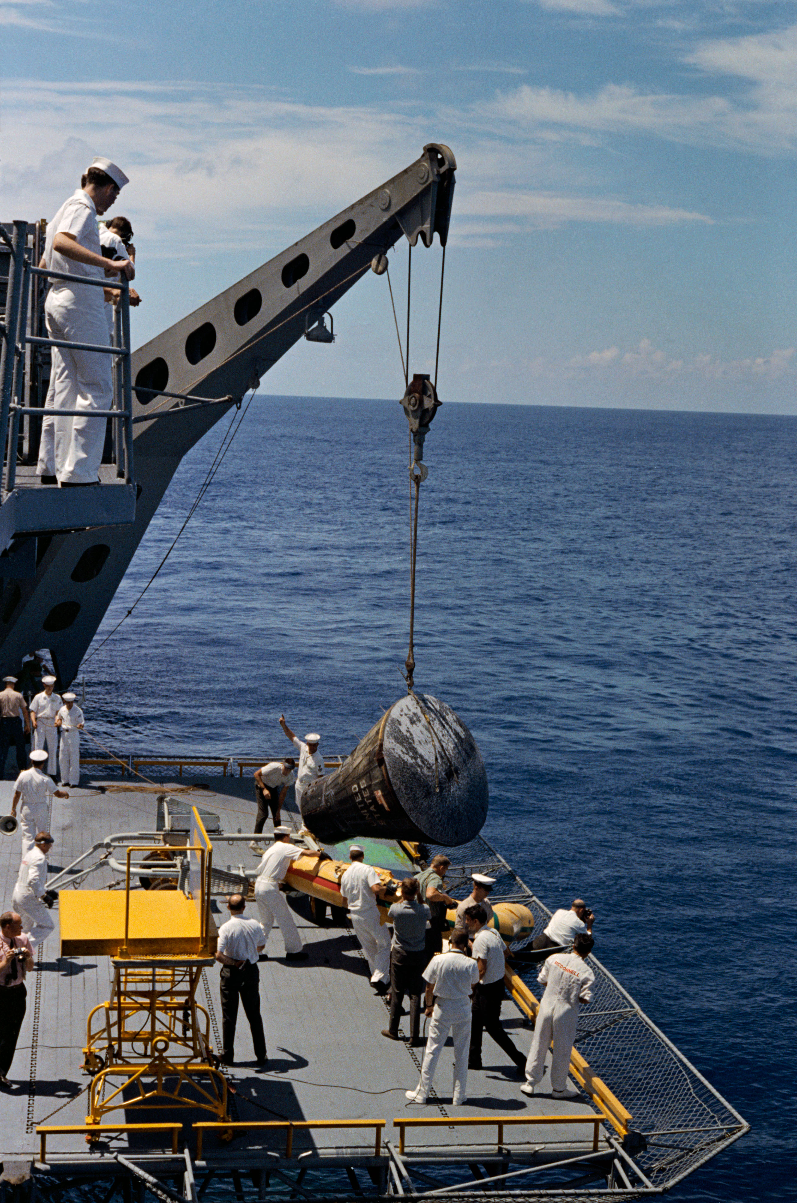 Blackened and scorched following a fiery descent through the atmosphere, Gemini V is lowered by crane onto the deck of the U.S.S. Lake Champlain on 29 August 1965, after the United States' longest manned mission to date. Photo Credit: NASA