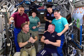 Incoming Expedition 43 Commander Terry Virts (front left) accepts the microphone from outgoing Expedition 42 Commander Barry "Butch" Wilmore during Tuesday's change-of-command ceremony. Photo Credit: NASA