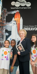 Lynda Oschin with students from the Science Center School. Students unfurled a banner displaying newly named Samuel Oschin Air and Space Center, future permanent home of the Space Shuttle Endeavour. Photo Credit: Leroy Hamilton (used with permission)