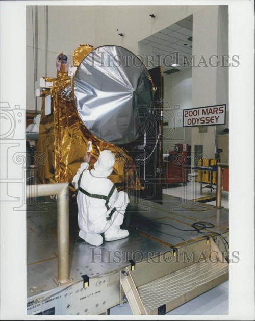 The Mars Odyssey spacecraft with its large dish Earth relay antenna is pictured at the Kennedy Space Center in 2001 being prepared for launch. Photo Credit: NASA