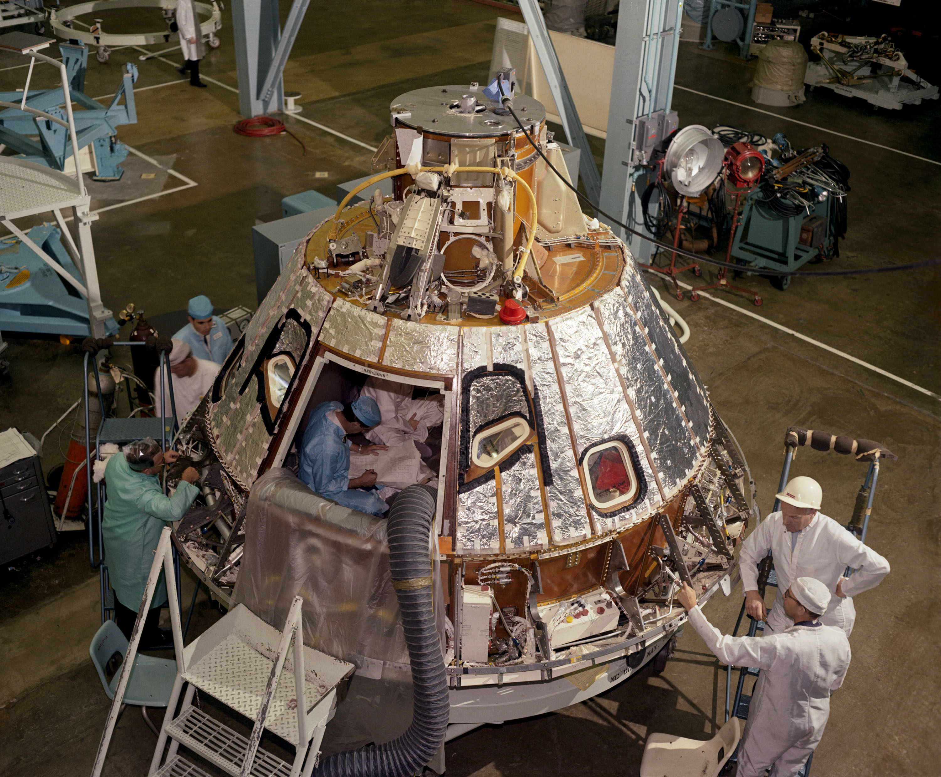 North American technicians work inside the Block I Command Module during processing. This craft caused great concern to Apollo 1 Commander Virgil "Gus" Grissom, who followed its progress with mounting distress and anger. Photo Credit: NASA