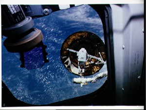 Armed with the capture bar mechanism, Pierre Thuot provides a measure of scale of the enormous size of Intelsat 603. Photo Credit: NASA