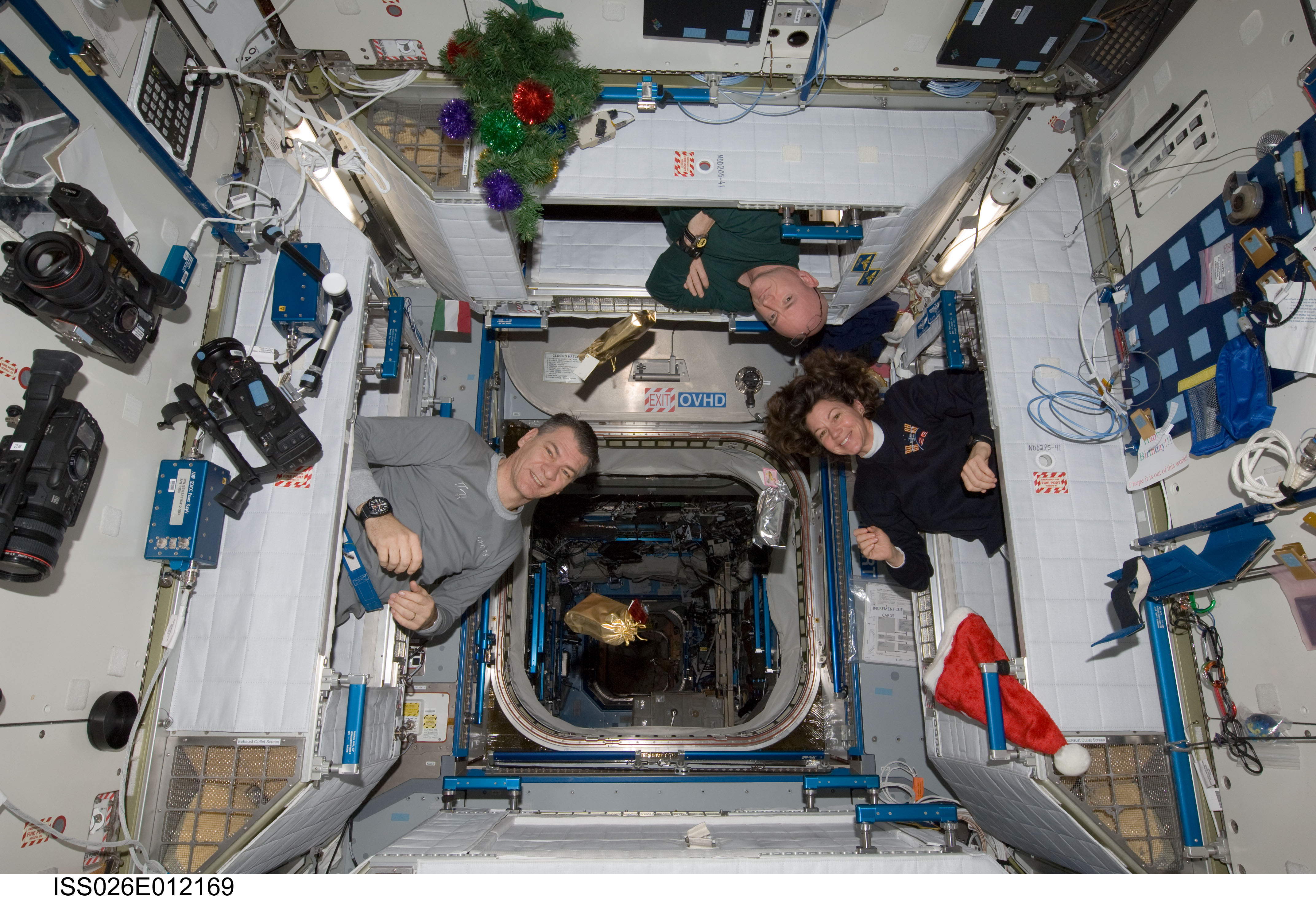 Expedition 26 crew members Paolo Nespoli (left), Scott Kelly (top) and Catherine "Cady" Coleman bail out of their sleeping quarters in the Harmony node of the International Space Station (ISS) on Christmas morning in 2010. Photo Credit: NASA