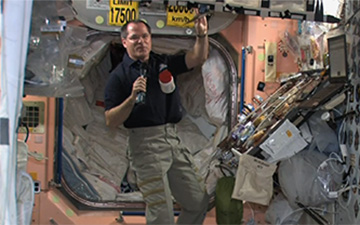 Commander Kevin Ford introduces his televised audience to the fare which was eaten by himself and Expedition 34 crewmates Oleg Novitsky and Yevgeni Tarelkin on Thanksgiving Day last year. Ford expressed particular thanks to the ground control teams for keeping his crew safe and operational. Photo Credit: NASA