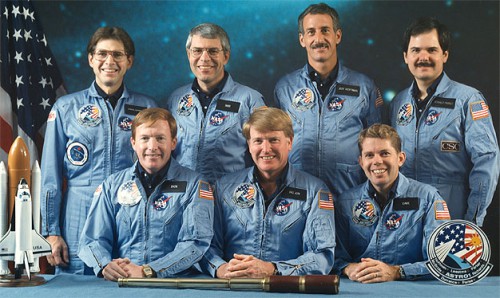 Had Challenger not been lost, these seven men were the next scheduled Shuttle crew. Seated from left to right are Pilot Dick Richards, Commander Jon McBride and Mission Specialist Dave Leestma, the 'orbiter' crew in charge of Shuttle systems. Standing from left to right are the 'science' crew: Payload Specialist Sam Durrance, Mission Specialists Bob Parker and Jeff Hoffman and Payload Specialist Ron Parise. Photo Credit: NASA