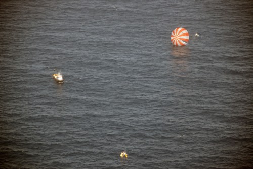 With one of its red-and-white main canopies visible in the water, Dragon is approached by recovery forces in the minutes after splashdown. Photo Credit: SpaceX