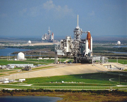 Pictured in September 1990, the problem-plagued STS-35/Columbia stack is shown in the foreground, on Pad 39A, with the STS-41/Discovery stack in the background on Pad 39B. Discovery would be the only orbiter to escape the disconnect crisis in the summer of 1991, but would succumb to her own problems the following year. Photo Credit: NASA