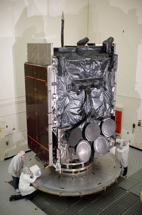 A 13,000 lb. U.S. Air Force WGS Wideband Global Satcom is pushed along the assembly floor at Boeing's plant in El Segundo, Ca. Note dish antennas by technicians for scale. Photo Credit: Boeing