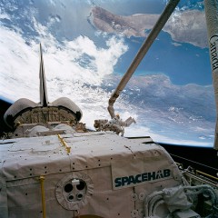 With the RMS robotic arm deftly operated by Nancy Sherlock, astronauts David Low and Jeff Wisoff are maneuvered around Endeavour's payload bay. The Spacehab module is clearly visible in the foreground. Photo Credit: NASA