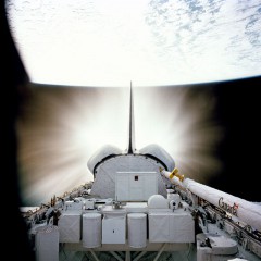 A bright flash of Challenger's Orbital Maneuvering System (OMS) engines illuminates the STS-7 payload bay, packed with equipment. Photo Credit: NASA