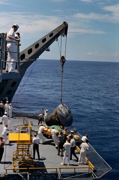 Blackened and scorched following a fiery descent through the atmosphere, Gemini V is lowered by crane onto the deck of the U.S.S. Lake Champlain on 29 August 1965, after the United States' longest manned mission to date. Photo Credit: NASA
