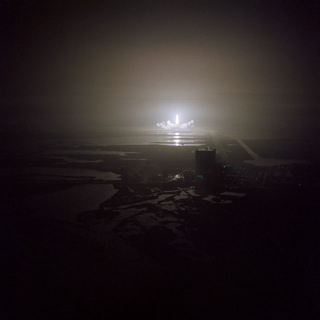 The STS-8 liftoff eerily illuminates the marshy expanse of the Kennedy Space Center. The giant Vehicle Assembly Building (VAB) is clearly visible in the foreground. Photo Credit: NASA