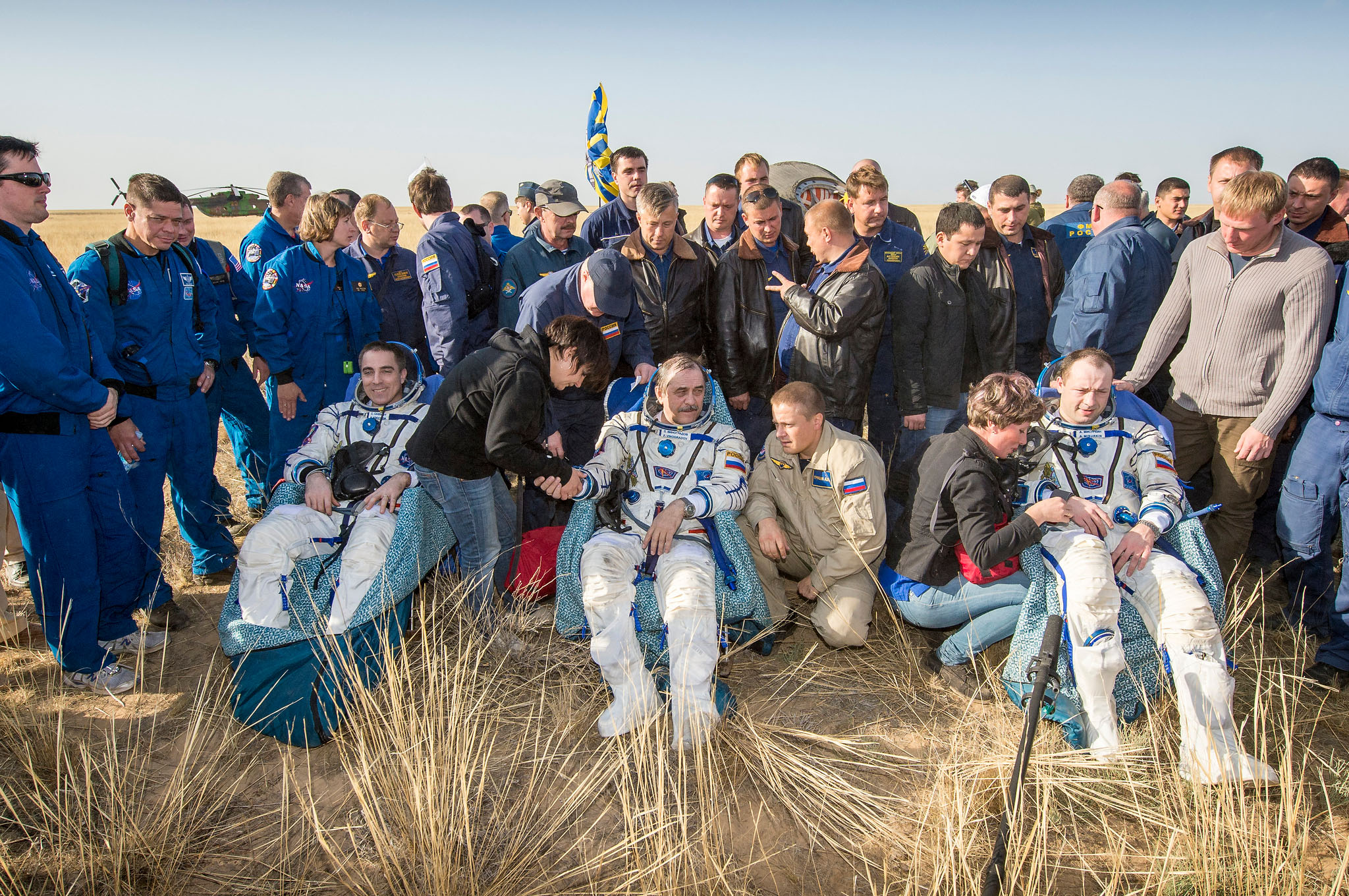 The returned Soyuz TMA-08M crew - from left, Chris Cassidy, Pavel Vinogradov and Aleksandr Misurkin - begin the process of readjusting to Earth's gravity after touchdown. They are surrounded by recovery personnel, friends and colleagues. NASA Chief Astronaut Bob Behnken is visible, second from left. Photo Credit: NASA