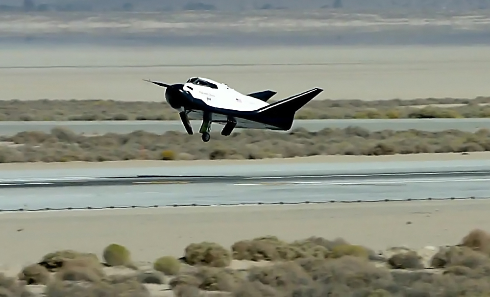 The Dream Chaser engineering test article coming in for an autonomous landing Saturday morning at Edwards Air Force Base, California.  As the image clearly shows, the left landing gear did not deploy properly, causing the vehicle to sustain minor damage on landing.  Photo Credit: SNC