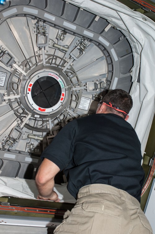 Expedition 37 astronaut Mike Hopkins prepares to open the hatch between Harmony's nadir port and the ORB-D Cygnus cargo ship, early in berthed operations. Photo Credit: NASA