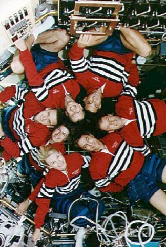 Demonstrating the roomy nature of the Spacelab module, the seven-strong STS-58 crew stretches their legs in this traditional in-flight portrait. Photo Credit: NASA