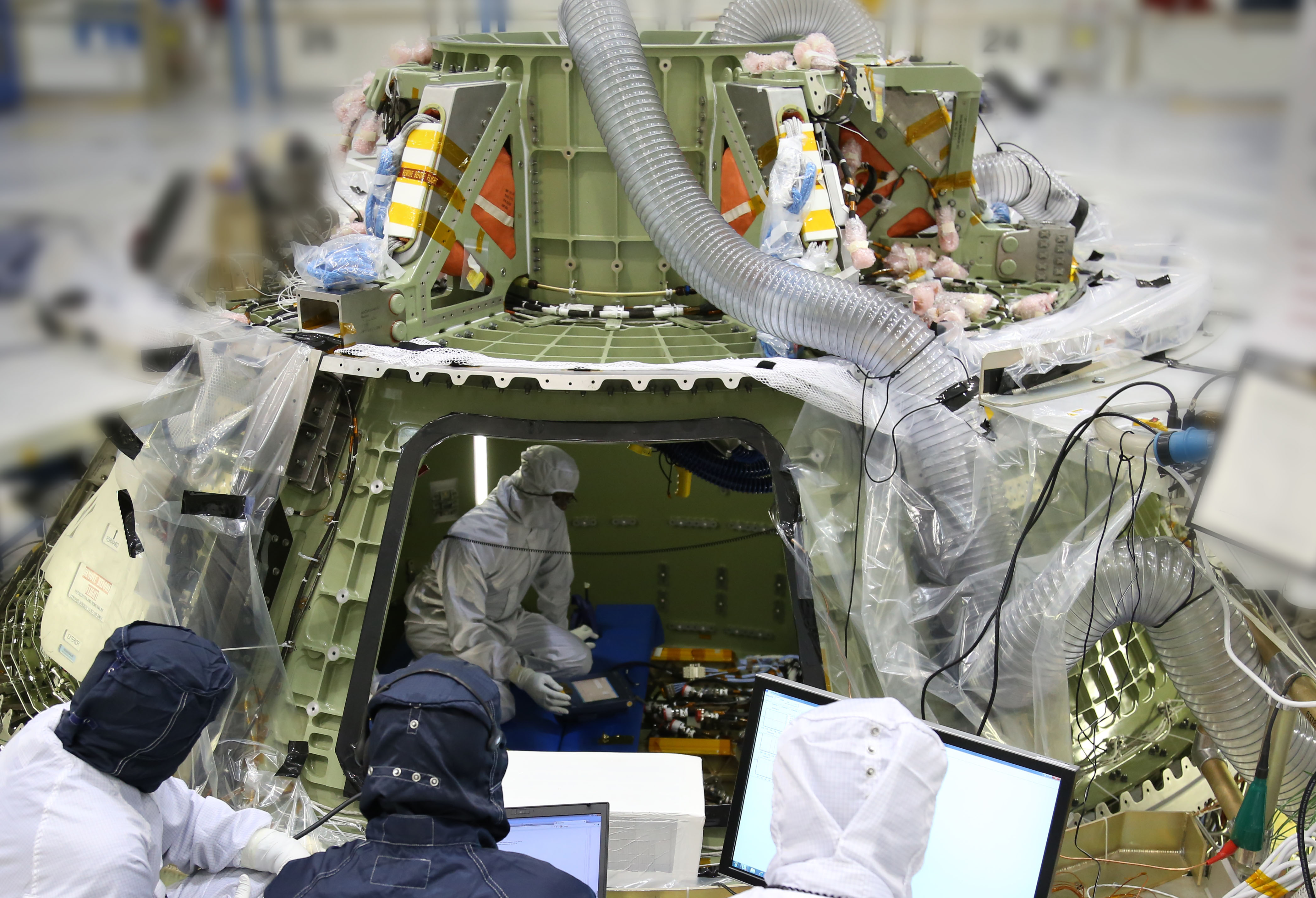Technicians work inside the Orion crew module being built at Kennedy Space Center to prepare it for its first power on. Turning the avionics system inside the capsule on for the first time marks a major milestone in Orion’s final year of preparations before its first mission, Exploration Flight Test Photo Credit: Lockheed Martin