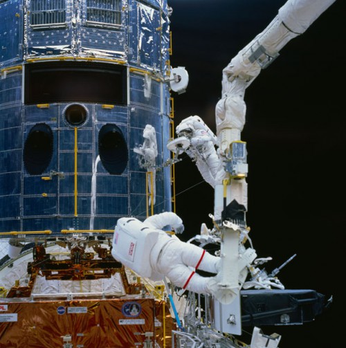Jeff Hoffman (with red stripes on the legs of his suit) and Story Musgrave work on the Hubble Space Telescope. Photo Credit: NASA