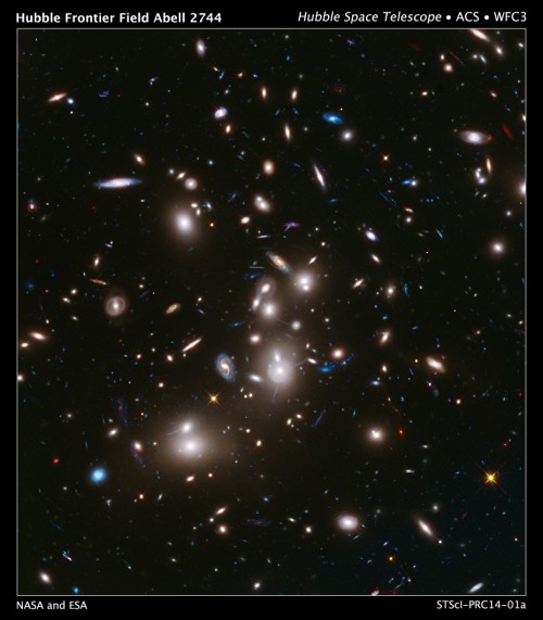 A long-exposure image of galaxy cluster Abell 2744, obtained by the Hubble Space Telescope, as part of the Hubble Frontier Fields program. The long blue streaks surrounding the cluster in the image, come from the light of much more distant galaxies, located as far as 13 billion light-years away behind the cluster. Image Credit: NASA/ESA, and J. Lotz, M. Mountain, A. Koekemoer, and the HFF Team (STScI)