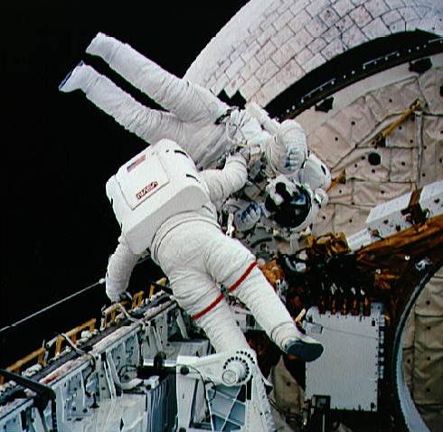 Greg Harbaugh (with red stripes on the legs of his suit) and Mario Runco perform mass-movement tasks during their EVA. Photo Credit: NASA