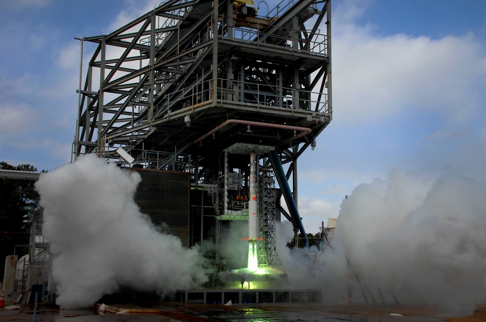 A 5-percent scale model of the Space Launch System (SLS) is ignited for five seconds to measure the effects acoustic noise and pressure have on the vehicle at liftoff. The green flame is a result of the ignition fluid that is burned along with the propellant during this short-duration test. Image and caption credit: NASA/MSFC/David Olive