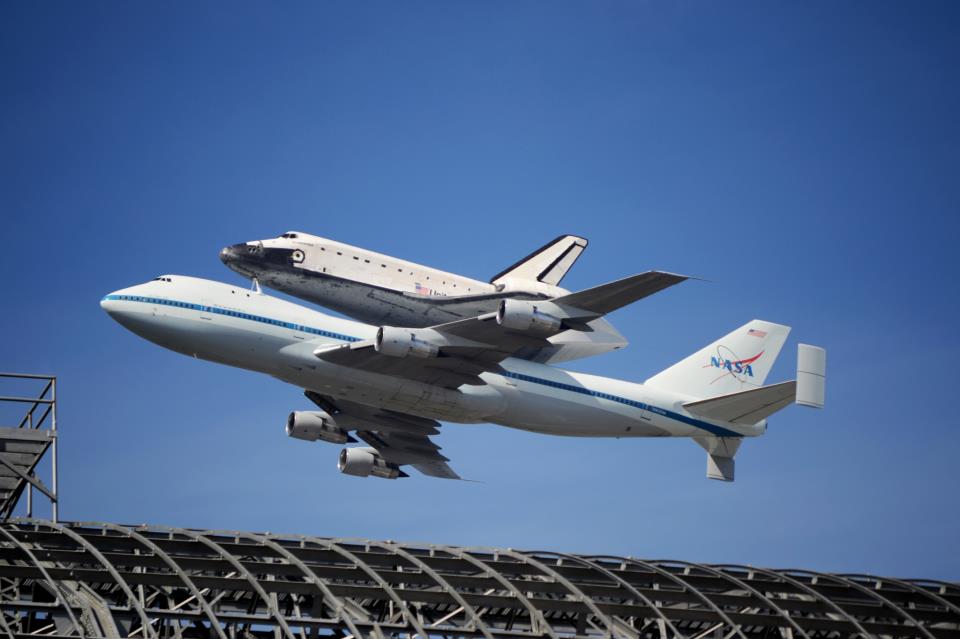 The space shuttle Endeavour, flying piggyback atop NASA's 747 SCA, flying over Moffett's Hanger One en route to Los Angeles, CA in Sep. 2012. Photo Credit: Christopher Calubaquib (Twitter.com/ChrisAstro)