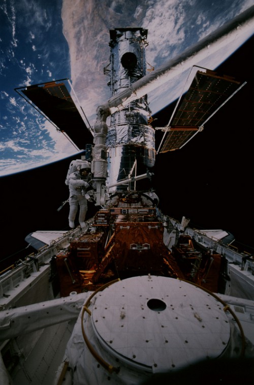 Steve Smith works on Hubble during EVA-3. The new external airlock, which was making its first flight on STS-82, is clearly visible in the foreground. Photo Credit: NASA