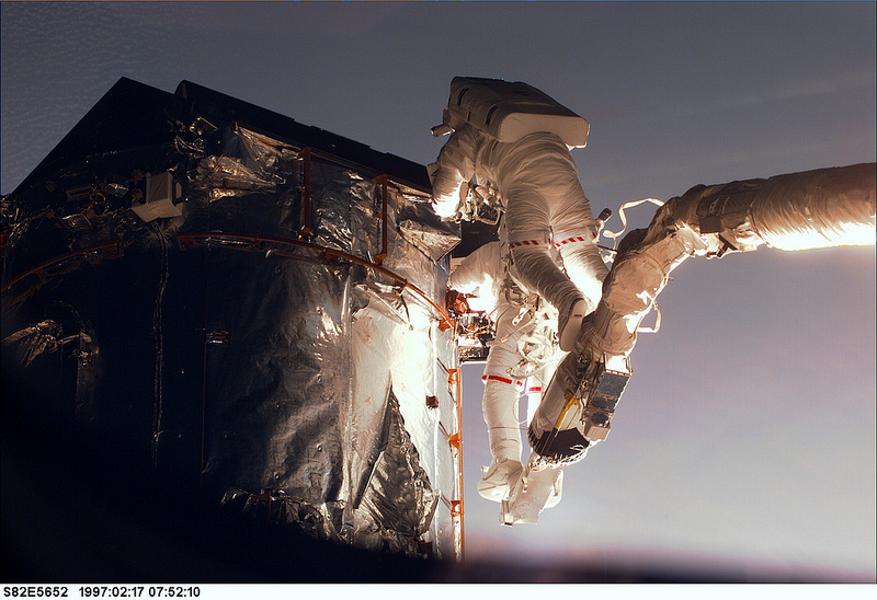 At the very 'top' of the Hubble Space Telescope, astronauts Greg Harbaugh (left) and Joe Tanner work on the magnetometer cover task. Mark Lee compared Tanner's ascent to riding his Harley. Photo Credit: NASA