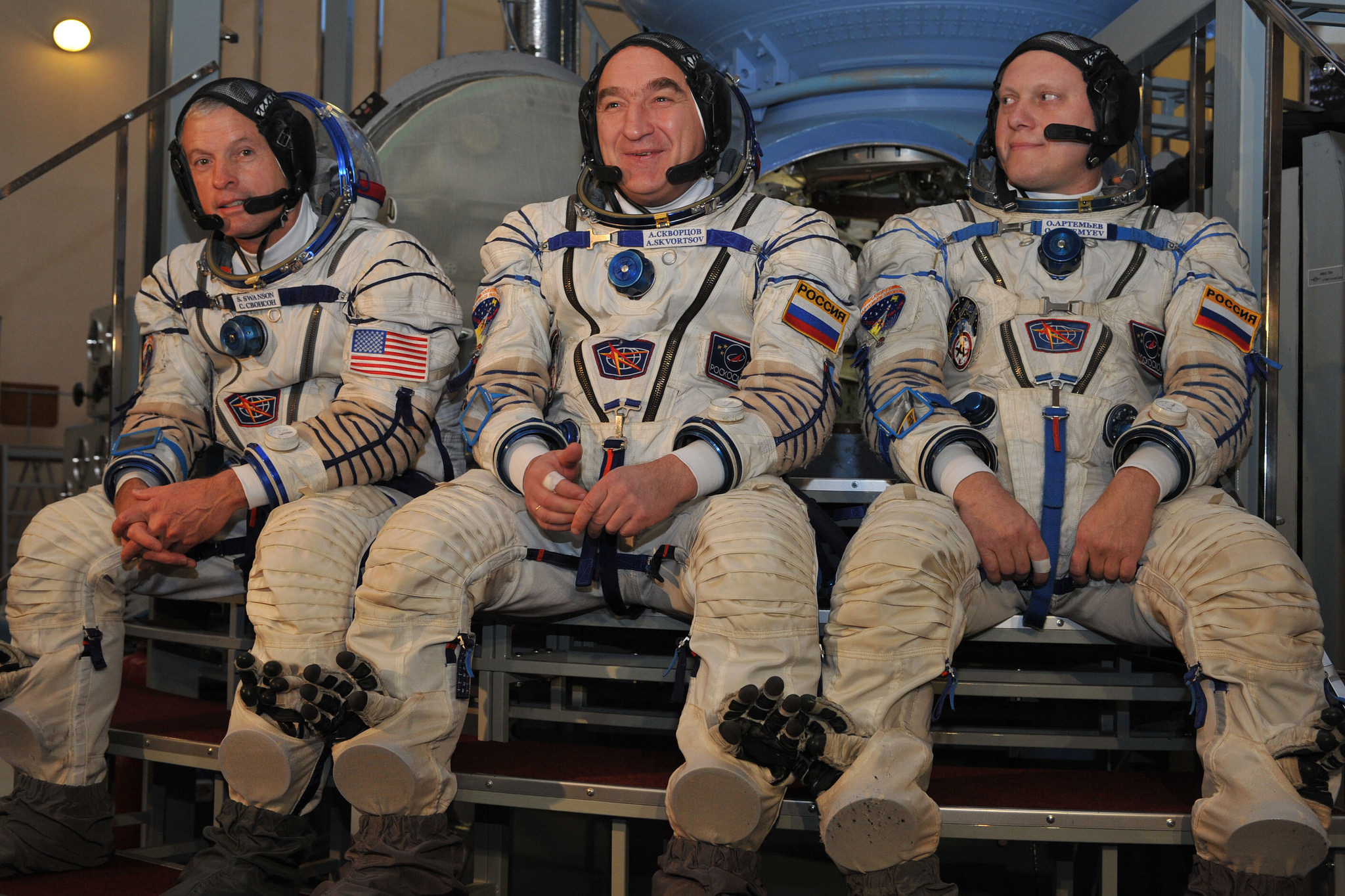 Pictured in their Sokol ("Falcon") launch and entry suits, in front of the Soyuz simulator, at the start of final exams on 5 March 2014, the Soyuz TMA-12M crew fields questions from journalists. Left to right are Steve Swanson, Aleksandr Skvortsov and Oleg Artemyev. Photo Credit: NASA