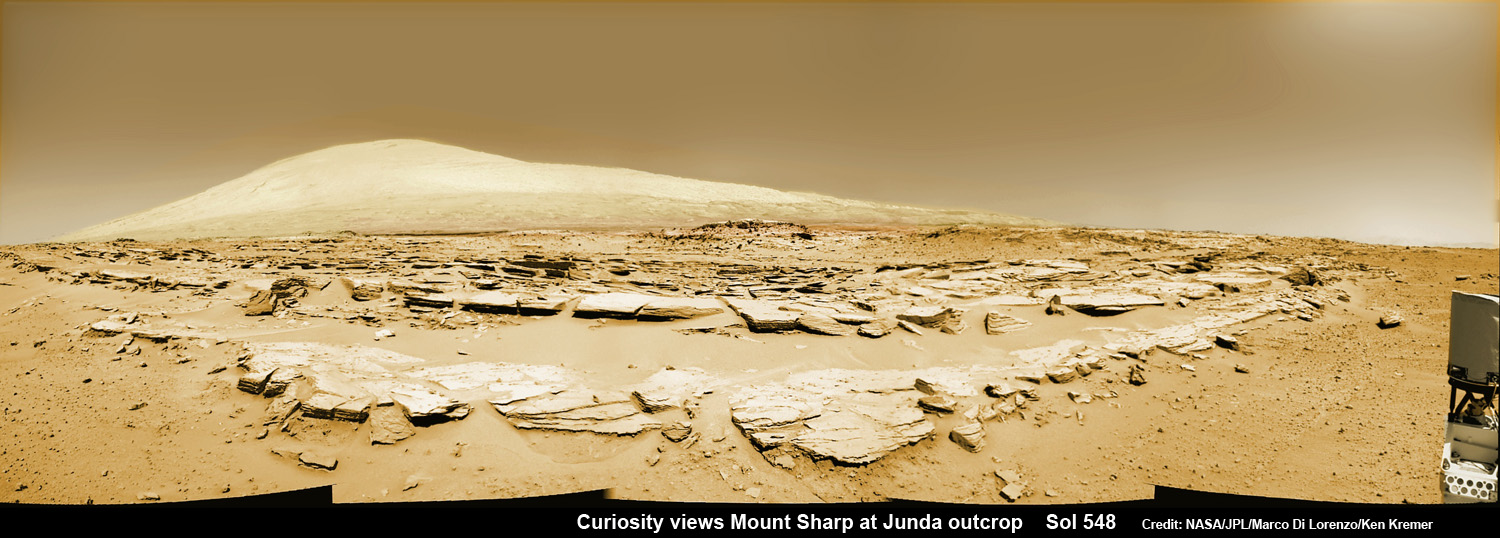 Martian landscape scene with rows of striated rocks in the foreground and Mount Sharp on the horizon. NASA's Curiosity Mars rover paused mid drive at the Junda outcrop to snap the images for this navcam camera photomosaic on Sol 548 (Feb. 19, 2014) and then continued traveling southwards towards mountain base.    Credit: NASA/JPL-Caltech/Marco Di Lorenzo/Ken Kremer-kenkremer.com