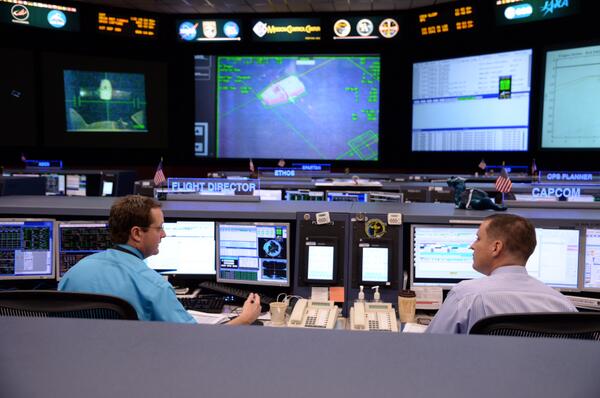 Flight Director Matt Abbott (left) and Capcom Jack Fischer confer in the Mission Control Center, ahead of today's capture of the CRS-3 Dragon. Photo Credit: NASA