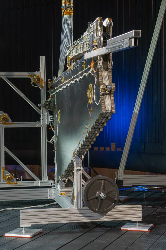 The stowed package is only 4-½ inches thick; this slim packaging allows MegaFlex to fit optimally within tight launch fairings. The wing unfolds in three phases: Staging, extension, and unfurling. In the foreground is a simple test-use-only counterweight which is bolted to the section of the wing that extends, to provide offloading of gravity effects.