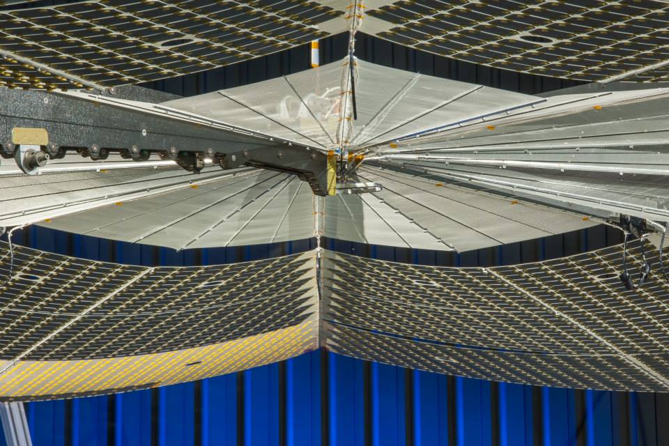 Shown here is the hub mechanism at the center of the wing, where the extended panels and spars that support the blanket meet. The spars rotate about this hub when the blanket is unfurled. The inner 10% of the area of the circle is not populated with solar cells, so that this section may be arranged extra compactly for launch. When the wing is stowed the spars are folded back against the main panel sections to reduce the overall length of the system to allow the greatest amount of power to be launched within a given length fairing.