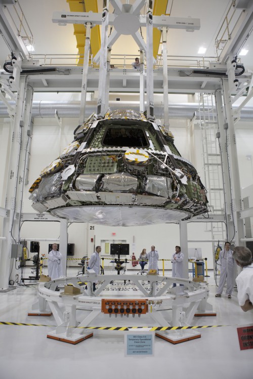 Inside the Operations and Checkout Building high bay at NASA's Kennedy Space Center in Florida, Lockheed Martin technicians monitor the progress as the Orion crew module is lifted by crane from a test stand for heat shield installation. Photo Credit: NASA / Dimitri Gerondidakis