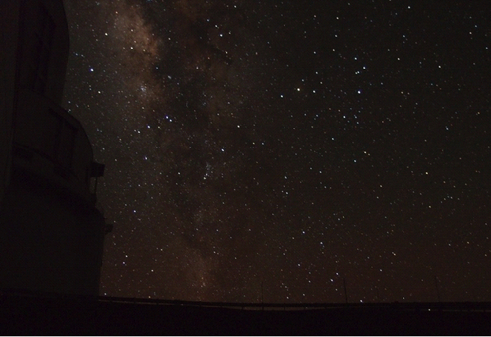The Subaru Telescope dome (left) is silhouetted by the Milky Way, as the telescope searches for KBOs. The search area is among the star clouds in the upper left of the image. Image Credit/Caption: John Spencer/JHU/APL
