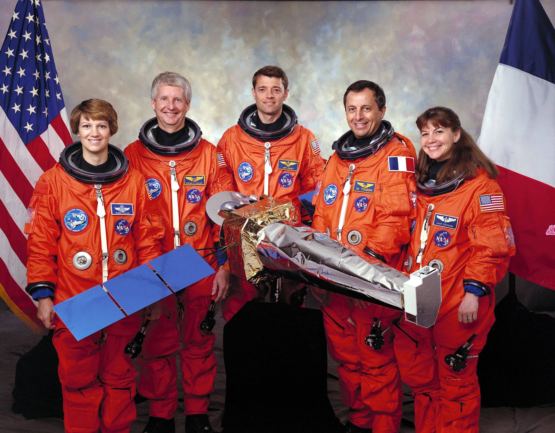 The STS-93 crew poses with a model of the Chandra X-Ray Observatory. This shuttle mission also entered into the history books for having the first female commander (Eileen Collins, here joined by Steven Hawley, Jerry Ashby, Michel Tognini, and Cady Coleman). Photo Credit: NASA
