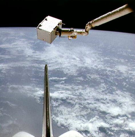 The Interim Environmental Contamination Monitor (IECM) is maneuvered by the RMS mechanical arm, close to Columbia's vertical stabilizer. Photo Credit: NASA