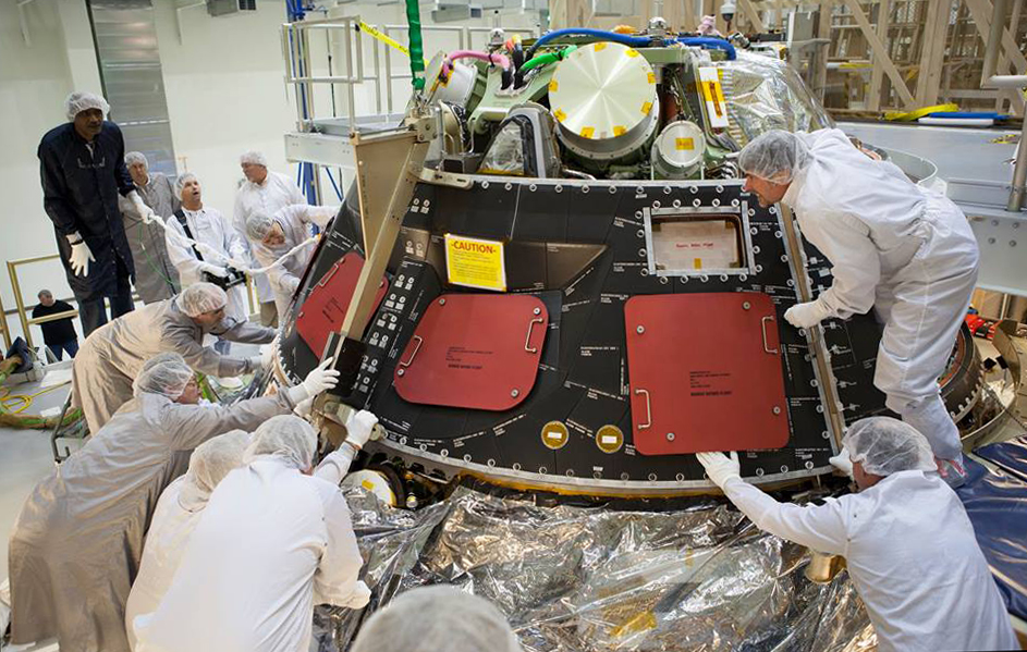 Inside the Operations and Checkout Building high bay at NASA's Kennedy Space Center in Florida, technicians dressed in clean-room suits install a back shell tile panel onto the Orion crew module. Photo Credit: NASA/Dimitri Gerondidakis