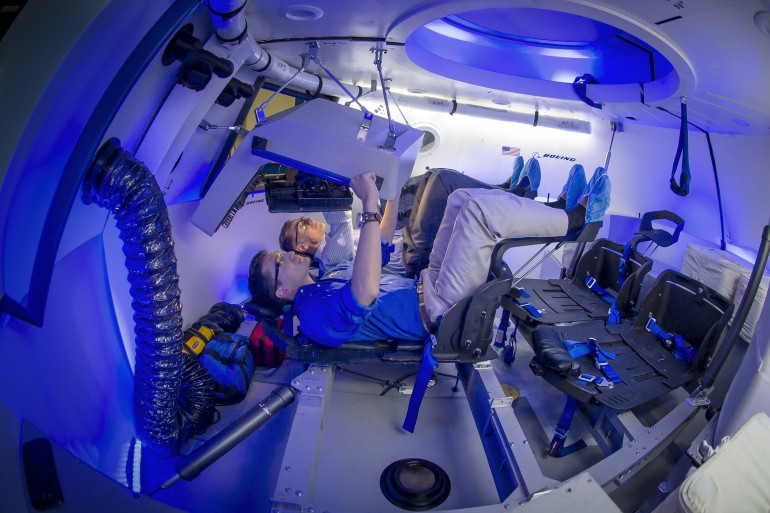 Boeing CST-100 engineer Tony Castilleja (front) and a fellow engineer (behind) work console inside the company's CST-100 mock up test article. Photo Credit: Boeing