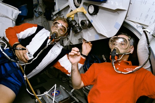 Mark Lee (left) and Carl Meade pre-breathe on masks, prior to their EVA. Photo Credit: NASA