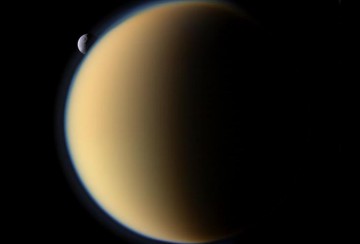 Titan accompanied by Tethys at upper left, one of Saturn's moons, in this image by the Cassini spacecraft. Titan's thick, opaque blue haze layer is clearly visible. Image Credit: ESA/NASA/JPL/Cassini Imaging Team