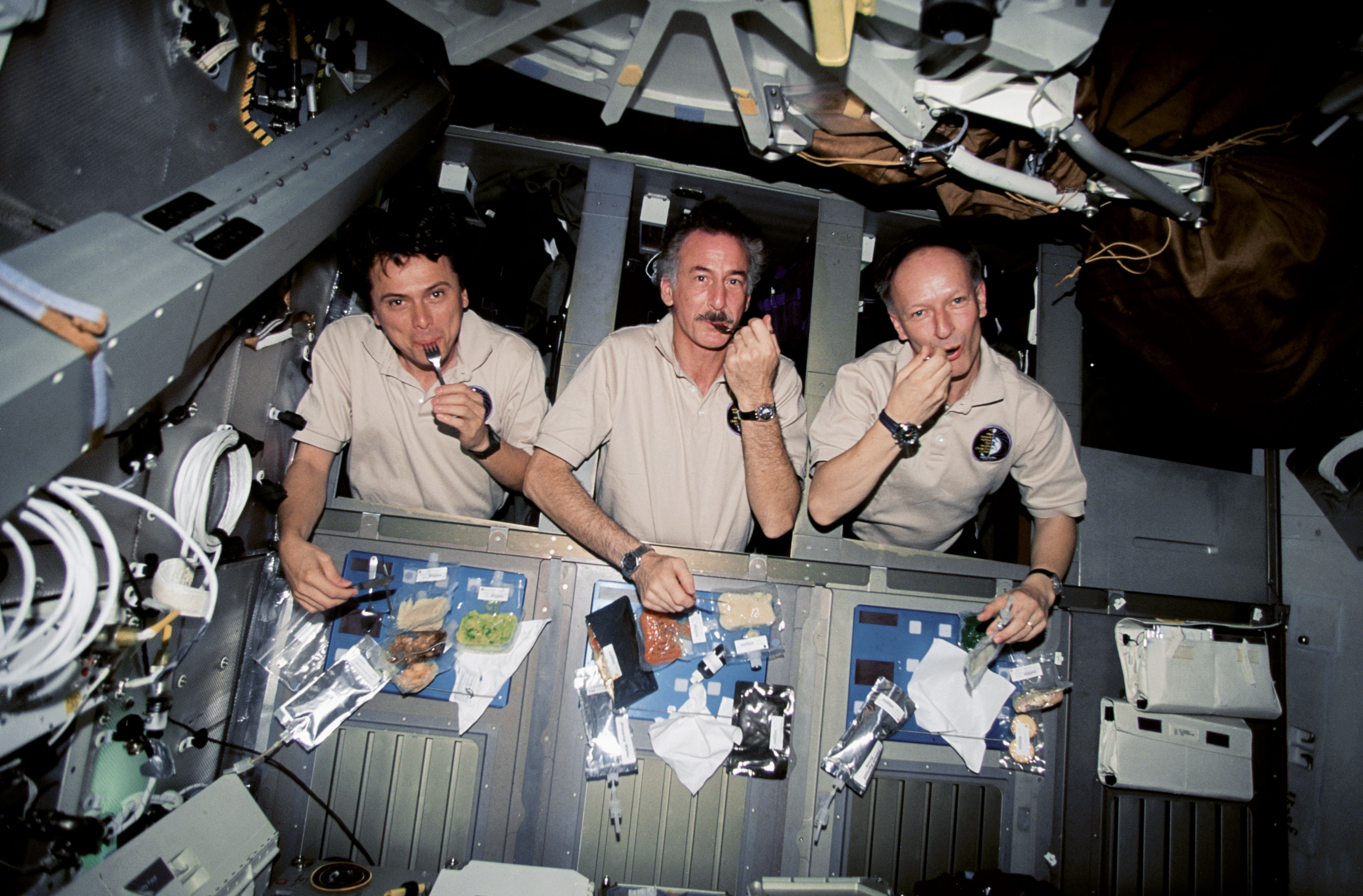 Franklin Chang-Diaz, Jeff Hoffman and Claude Nicollier enjoy a meal in their sleep stations during STS-75. Photo Credit: NASA