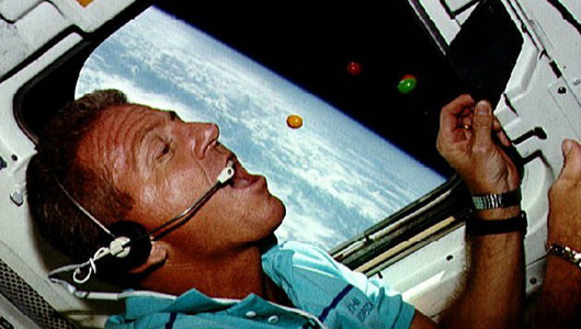 Loren Shriver gobbles a handful of M&Ms during STS-46, his third and final shuttle mission. Photo Credit: NASA
