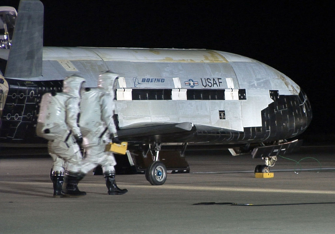 The X-37B during post-landing operations at Vandenberg Air Force Base after landing in 2010. Personnel in SCAPE suits (Self-contained atmospheric protective ensemble) are seen here conducting initial checks on the vehicle and ensuring the area is safe. Photo Credit: USAF