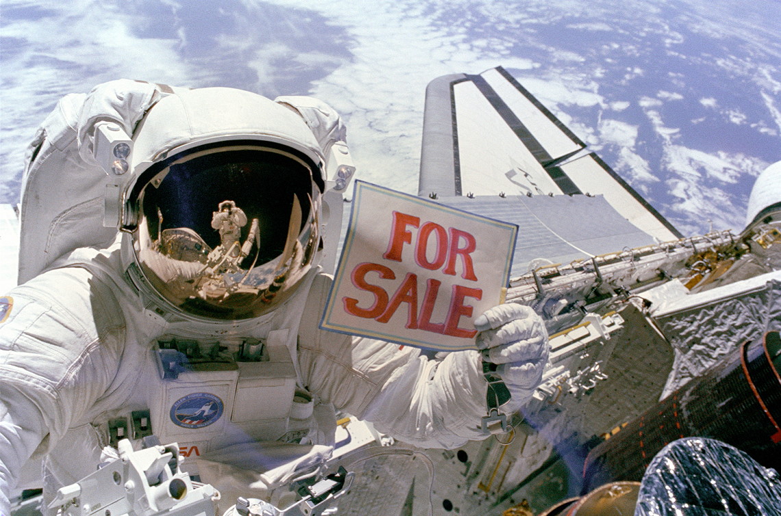 Dale Gardner holds up the famous "For Sale" sign to commemorate the successful salvage operation on Palapa-B2 and Westar-VI in November 1984. Photo Credit: NASA