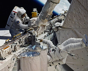Jeff Hoffman (left) and Dave Griggs during their contingency EVA attempt to reactivate the deployment switch on Syncom 4-3. Photo Credit: NASA