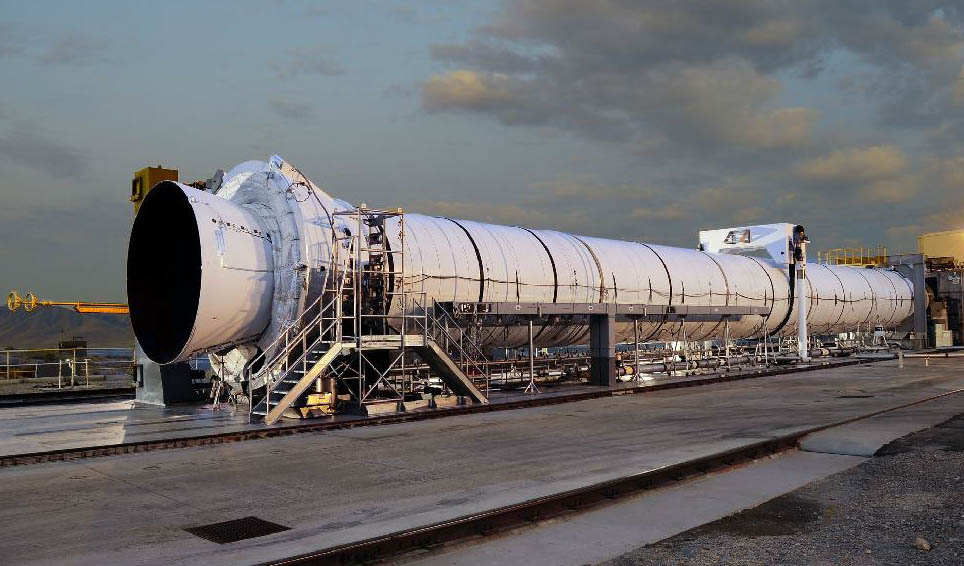 File photo of a five-segment ATK solid rocket booster on the company's test stand in Promontory, Utah. The 154-foot booster, which is in development for NASA's Space Launch System (SLS), will produce heat two-thirds the temperature of the sun, and its 12-foot-diameter cylinder will deliver 3.6 million pounds of thrust when the rocket ignites. The next full-scale test article for the SLS booster, Qualification Motor-1 (QM-1), is expected to ignite for a two-minute test fire in late March 2015. Photo Credit: ATK