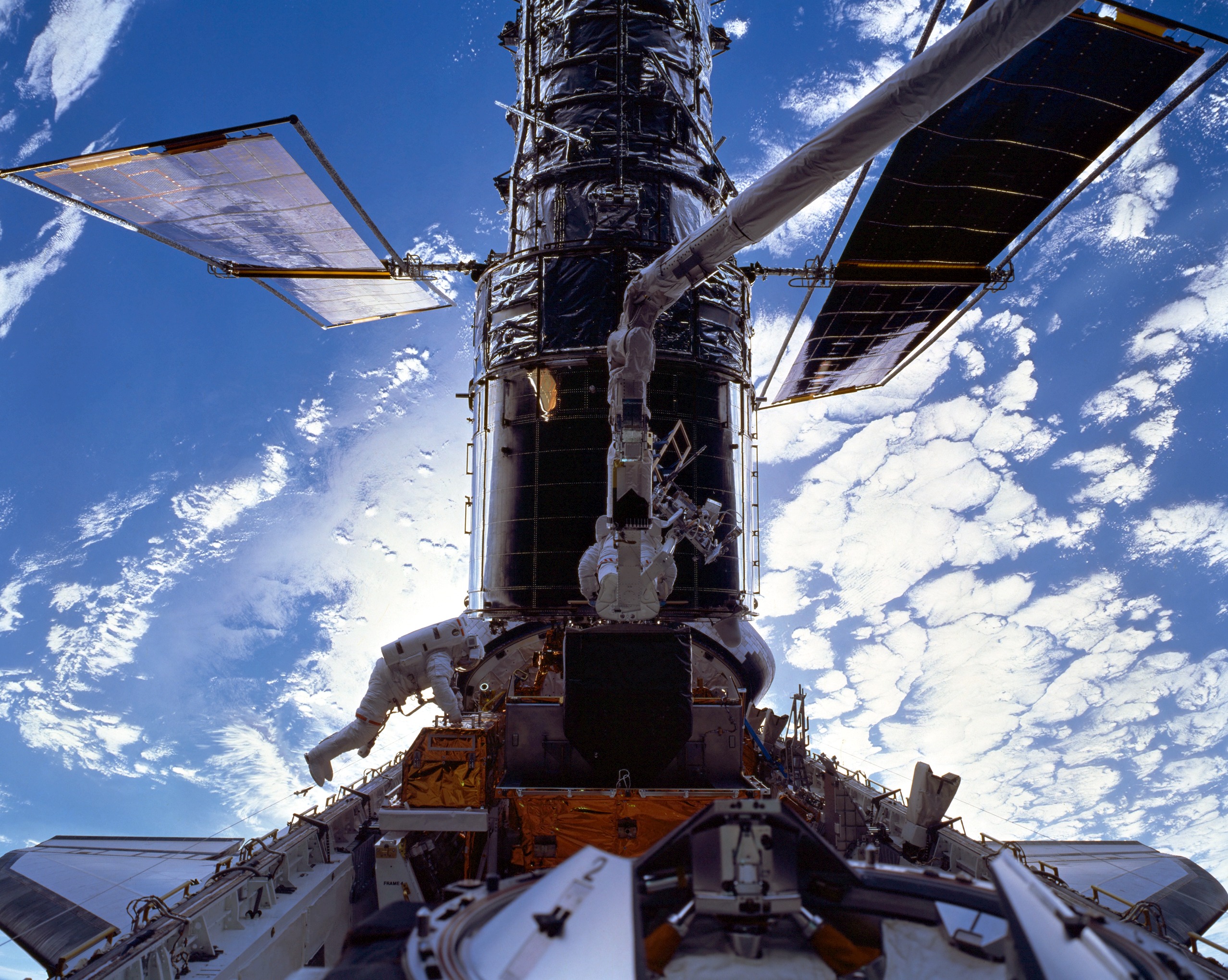 Astronauts Mike Foale (left) and Claude Nicollier work on the Hubble Space Telescope (HST) during their EVA-2. Photo Credit: NASA