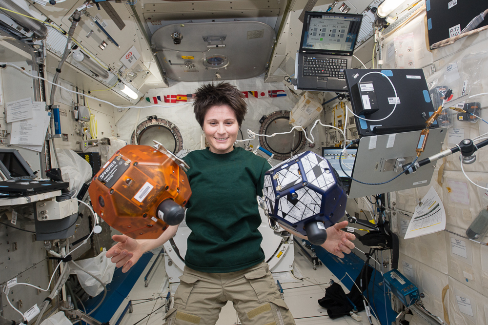 European Space Agency astronaut Samantha Cristoforetti works with a pair of Synchronized Position Hold, Engage, Reorient, Experimental Satellites, or SPHERES, on the International Space Station. Image Credit: NASA