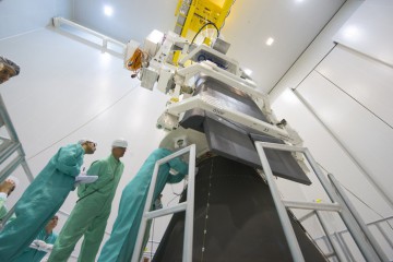 The IXV is shown being installed on its payload adapter, flanked by technicians. Photo Credit: ESA–M. Pedoussaut